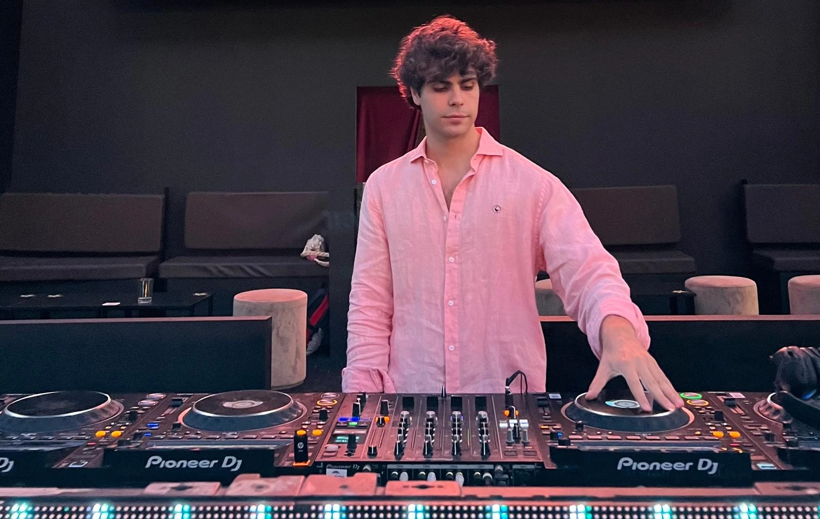 Pold Castin pinchando en directo con camisa rosa, detrás de una mesa Pioneer DJ